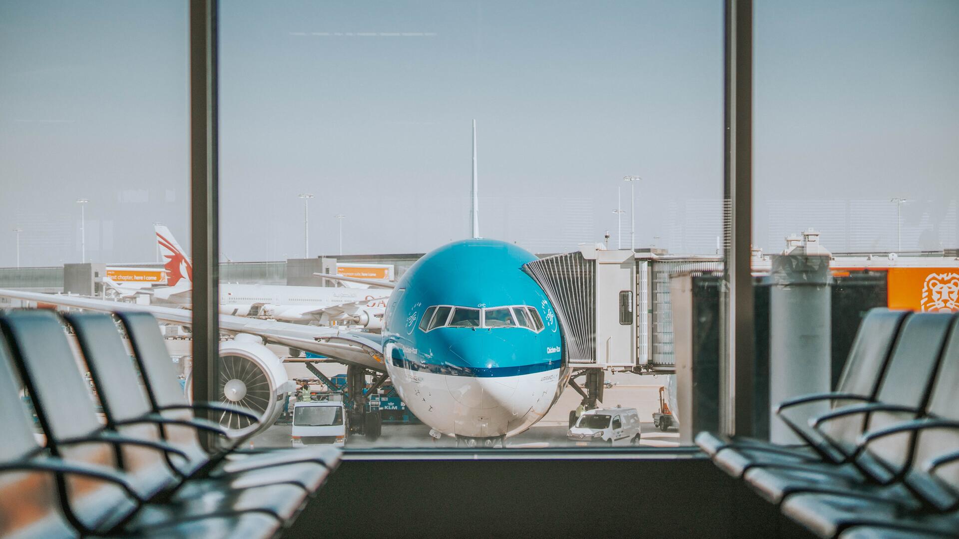 Blauw vliegtuig gezien van voren vanuit de wachtruimte bij de gate