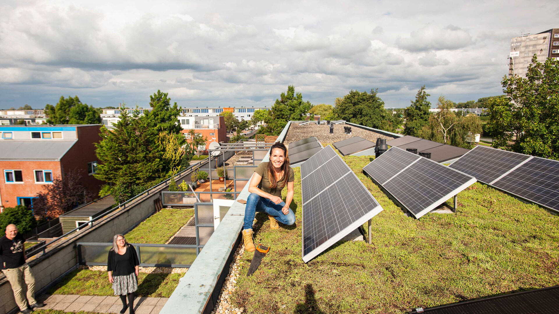 Vrouw zit op een vergroend dak naast zonnepanelen. 